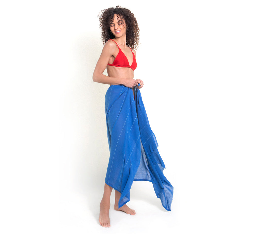 The Camellia wrap in Azure, a bight, summery blue, is worn by a model, pareo- or saraong-style over a red bikini. Our wraps  are luxuriously soft and versatile.  The tick-repellent scarf also repels mosquitoes, offering DEET-free protection.