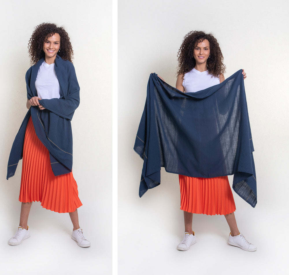 A model wears our mosquito-repellent wrap over her shoulders in one shot and holds it to show its ample size in another. Classic in navy, the insect-repellent scarf pairs well with the model's orange skirt and white tank top.