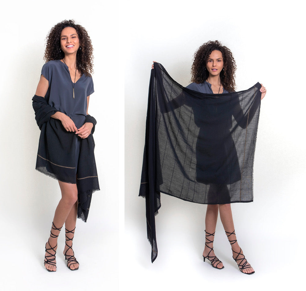 Insect-repellent cotton scarf in black is worn over a gray silk dress. The model holds the insect-repellent scarf up in front of her to show its size and transparency. You'd never know our tick-repellent and mosquito-repellent Shoo for Good Camellia shawl in black is so effective. Insect Shield permethrin is bound to the fibers of the scarf and is effective for 70 washings. An Oprah favorite for DEET-free protection.